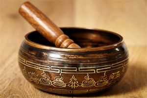 Close-up of a wooden Ayurvedic singing bowl with a pestle on a wooden surface.