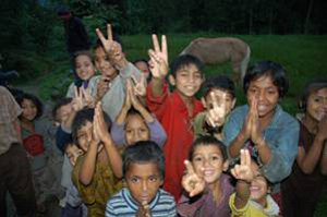 Smiling children showing peace signs in a tea garden community.