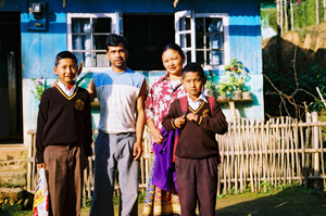 Family members standing outside their home in a tea garden.