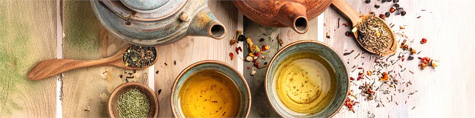 Assorted ceramic bowls and spoons with spices on a wooden surface