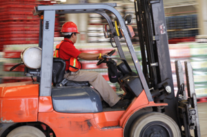 Person in red shirt operating a forklift in a warehouse.