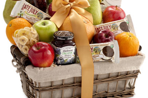 Woven gift basket filled with fruit, jam, and chocolates.