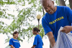  Volunteers, an adult and child, picking up trash outdoors.